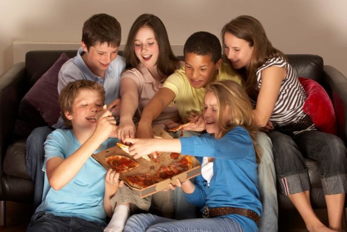 adolescenti che mangiano pizza con salumi: importanza dei salumi nell'alimentazione in adolescenza