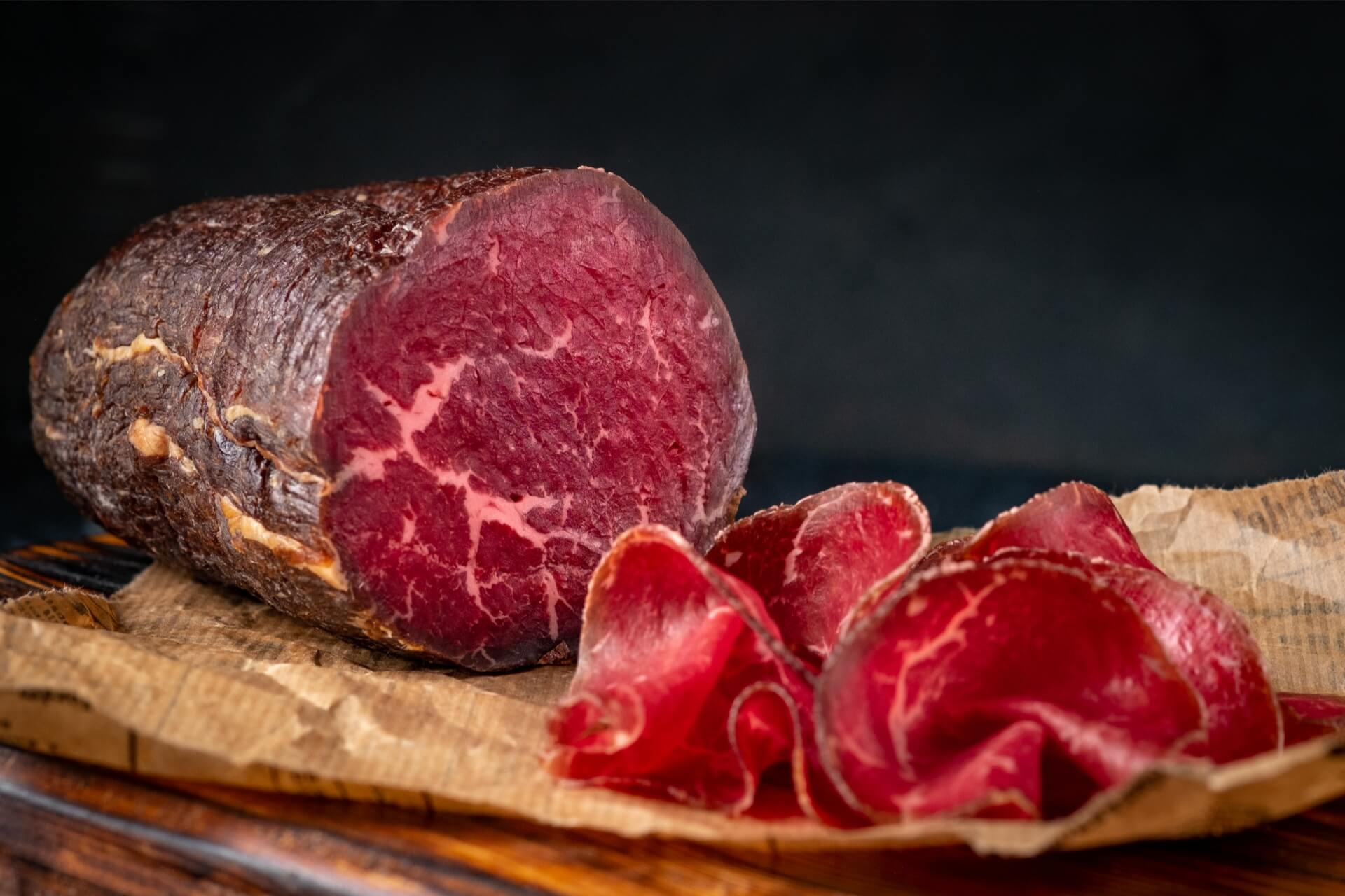 bresaola punta d'anca valtellinese affettata su tagliere di legno per un aperitivo