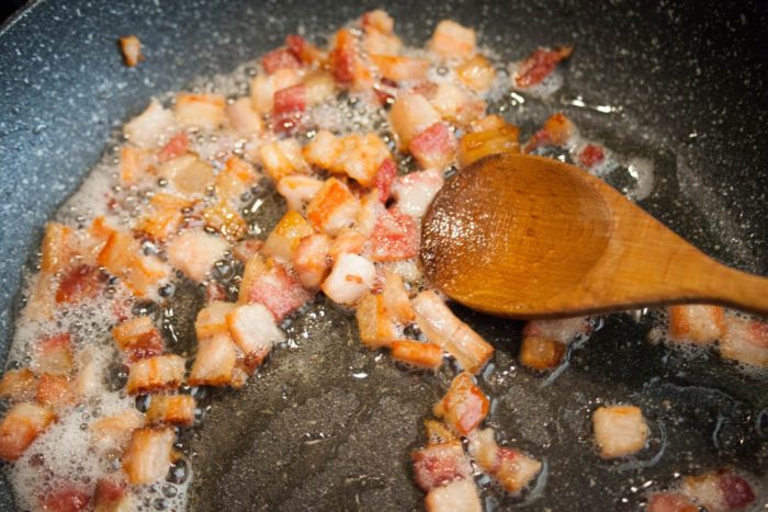 pancetta a cubetti passata in padella che rilascia il grasso della pancetta