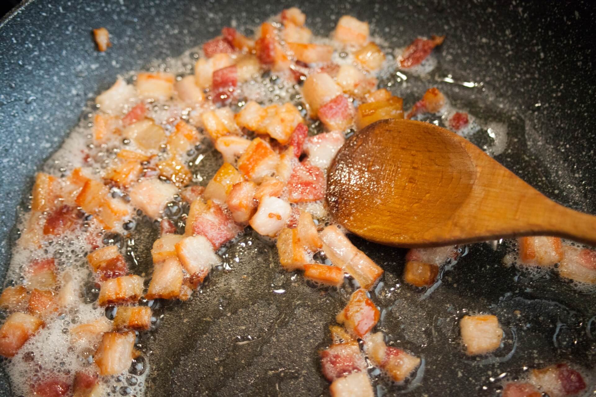 pancetta a cubetti passata in padella che rilascia il grasso della pancetta