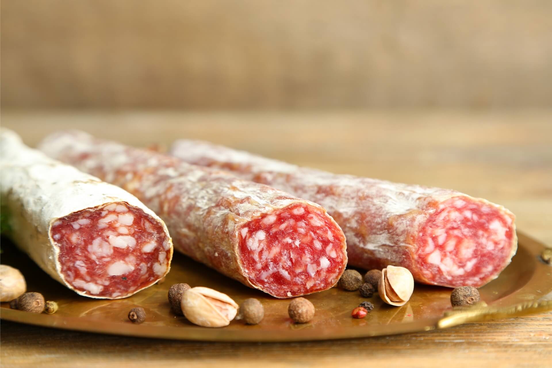 tipologie di salame dolce, affumicato e piccante su tagliere di legno